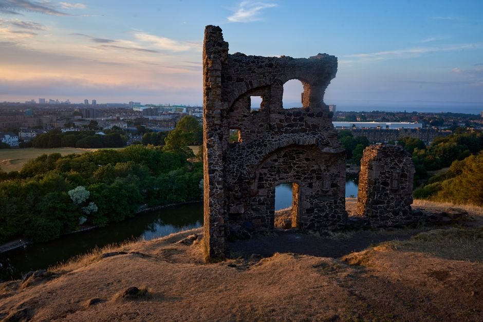 Anthony Ippolito Embraces Sylvester Stallone’s Persona for ‘I Play Rocky’ St. Anthony's Chapel ruins overlooking Edinburgh at sunset, captured from a hillside view.