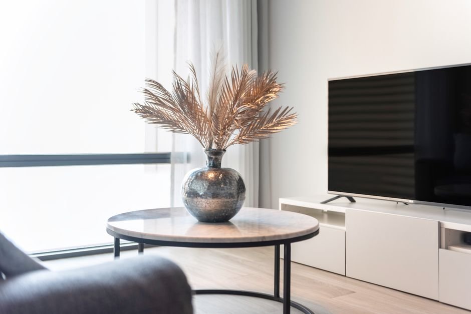 Short-Term Rentals Spark Community Disputes Across Indian Cities Stylish living room featuring a TV, table, and a vase with decorative leaves.