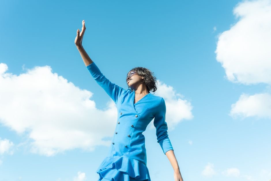 Skydance Confirms Separate Branding for Paramount+ and HBO Max Post-Merger Stylish woman in blue dress reaching up, set against a bright blue sky.