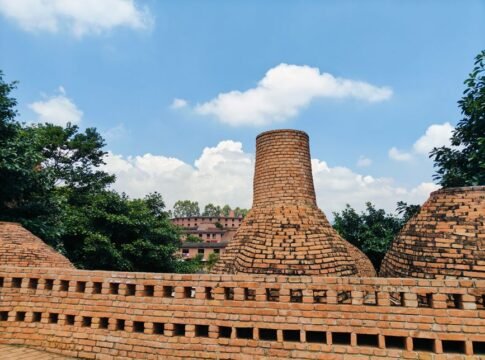 Traditional brick kilns under a clear blue sky surrounded by lush greenery. Traditional brick kilns under a clear blue sky surrounded by lush greenery.
