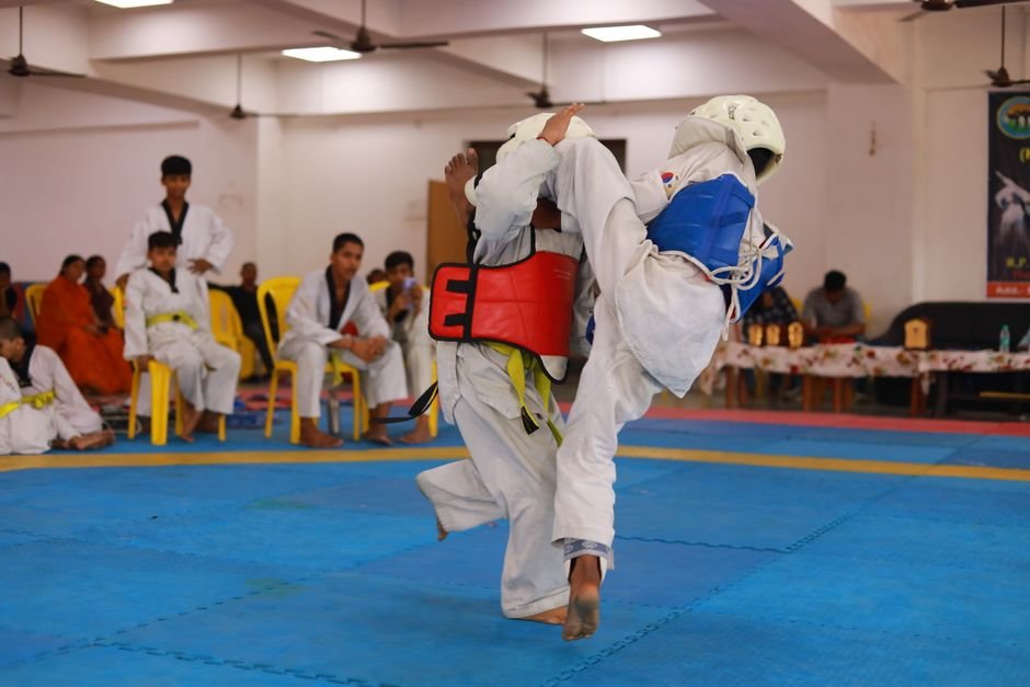 Jammu and Kashmir Wushu, Taekwondo Teams Clinch National School Games Trophies Two athletes engage in a high-energy taekwondo match in a gymnasium in India.